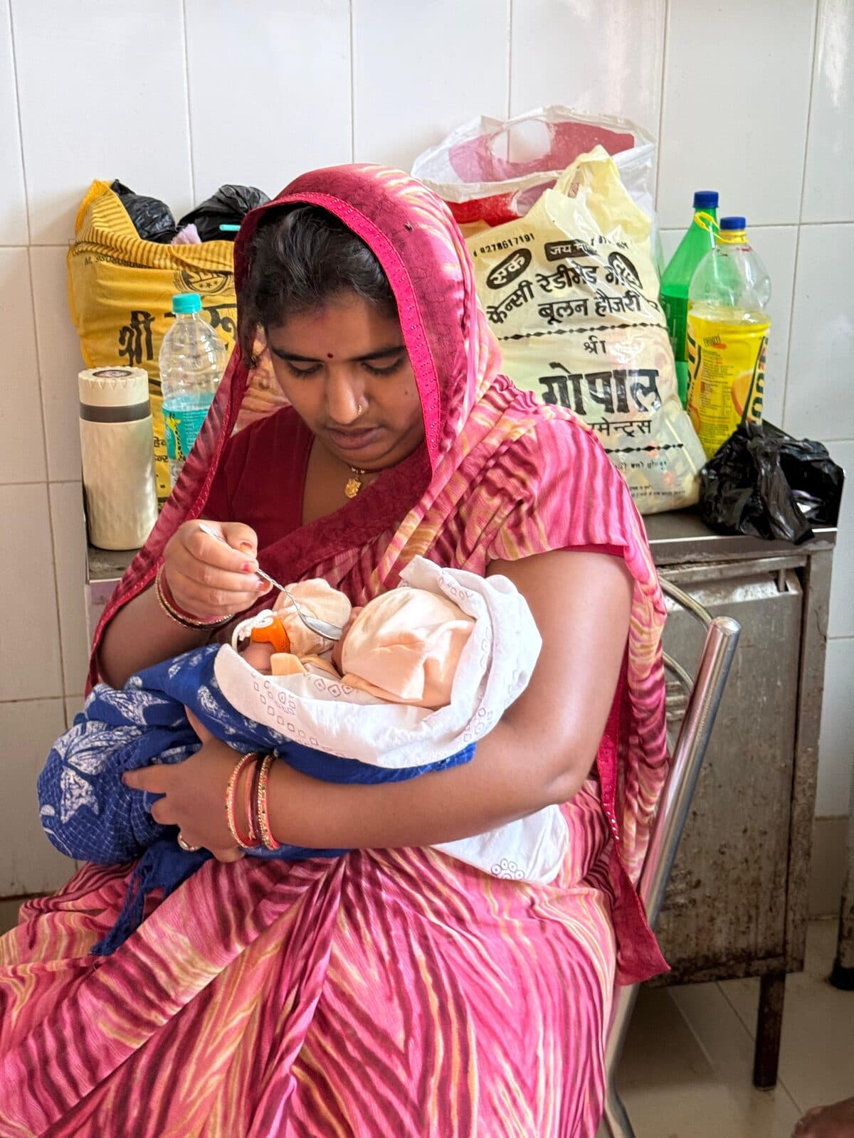 A mother feeds her baby, wearing the BEMPU TempWatch, at the Dholpur site
